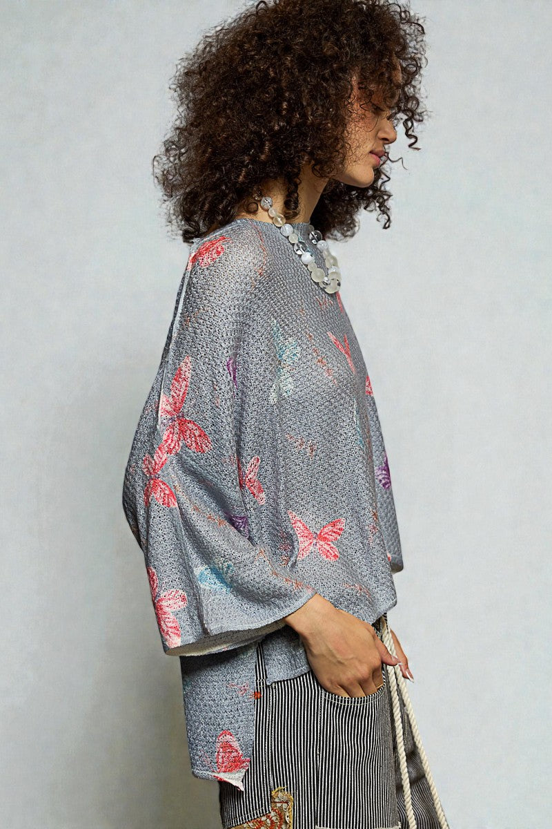 Woman wearing a gray kimono with butterfly patterns against a plain background