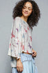 Woman wearing a butterfly-patterned top against a gray background