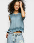 Woman wearing a denim top and shorts on a plain background