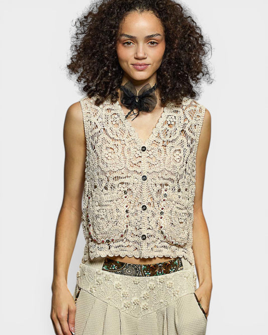 Woman wearing a beige lace top with a plain background