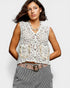 Woman wearing a white lace vest and striped pants on a plain background