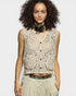 Woman wearing a beige lace top with a plain background