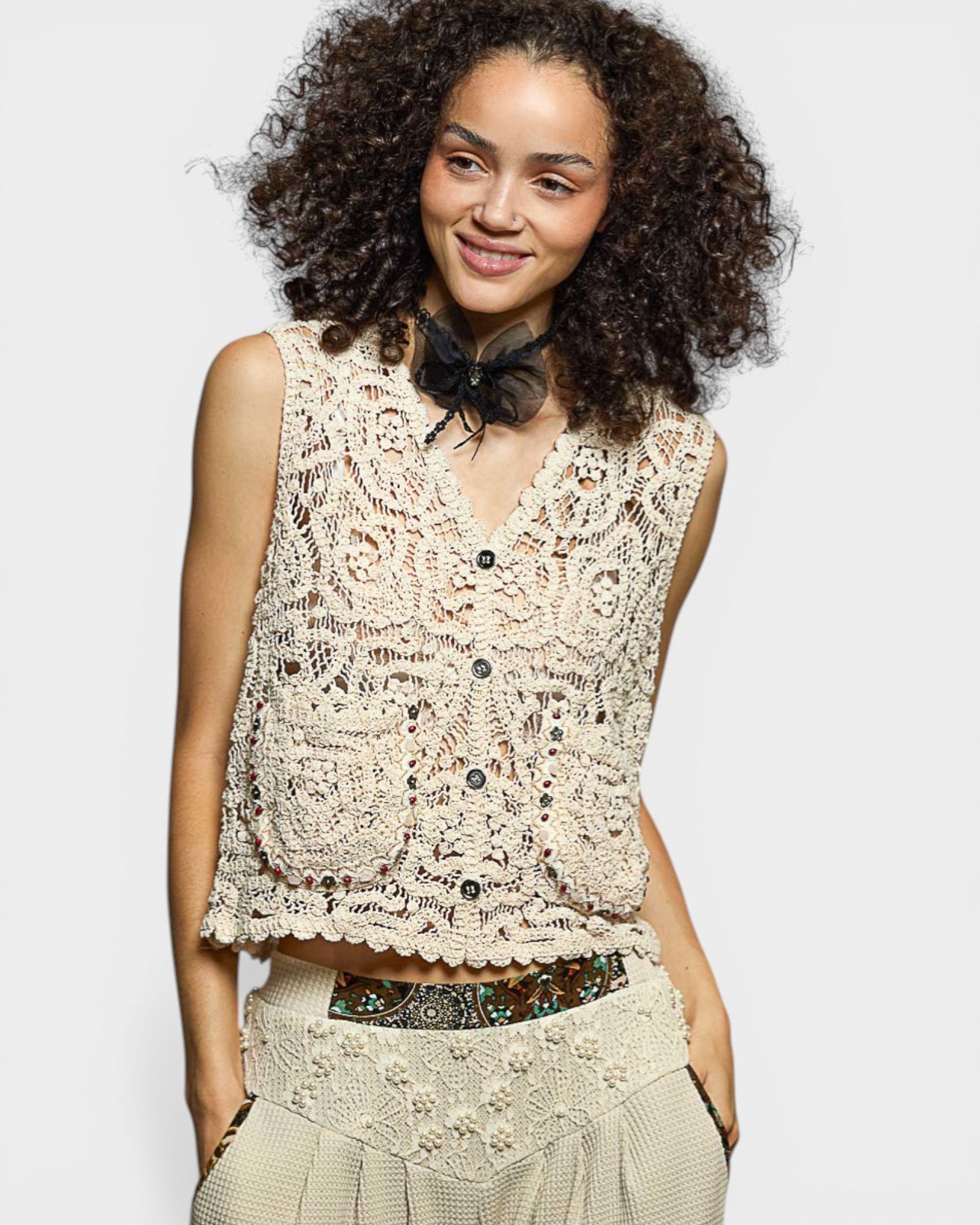 Woman wearing a beige lace top with a plain background