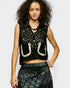Woman wearing a black lace top with cut-out design on a plain background