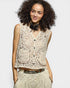 Woman wearing a beige lace top with a plain background