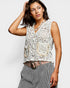 Woman wearing a sleeveless lace top with a belt on a plain background