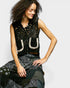 Woman wearing a black sleeveless top with white horseshoe designs on a plain background