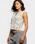 Woman wearing a sleeveless lace top with a plain background