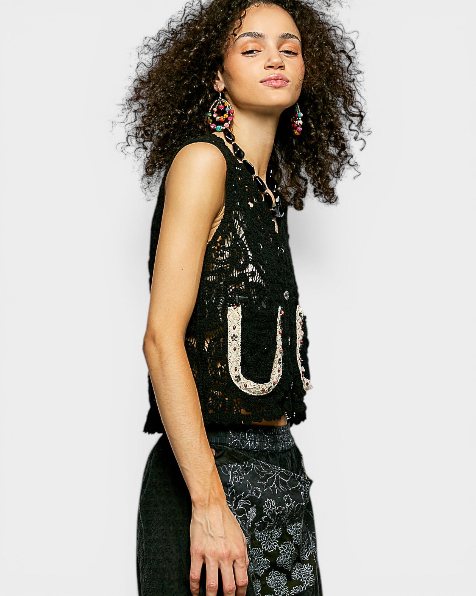 Woman wearing a black sequin top with floral patterns on a white background