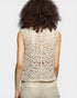 Person wearing a beige lace top against a plain background