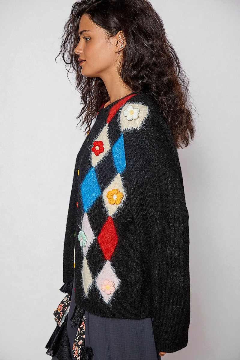 Woman wearing a colorful diamond pattern sweater against a plain background