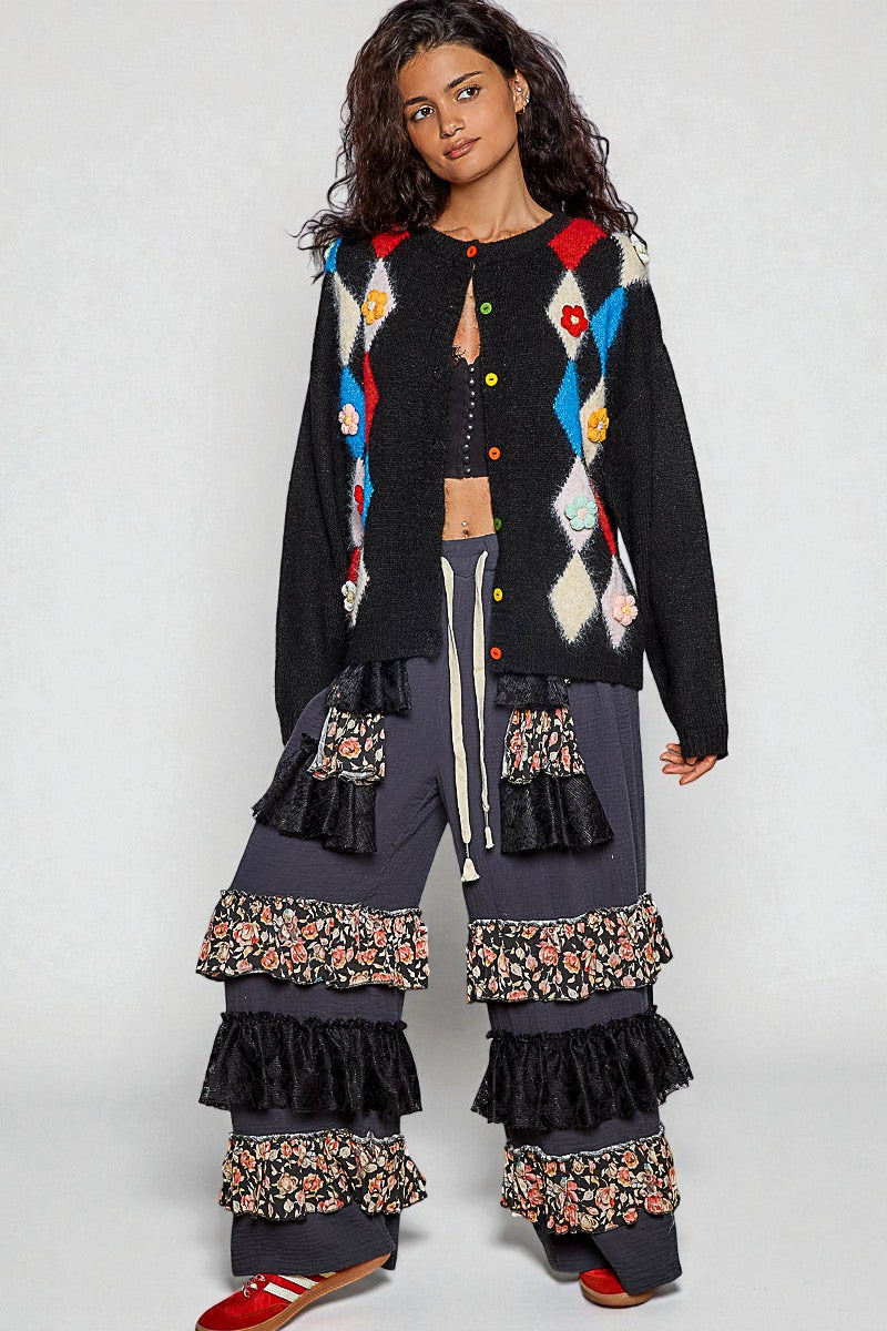 Woman wearing a colorful cardigan and layered pants on a white background