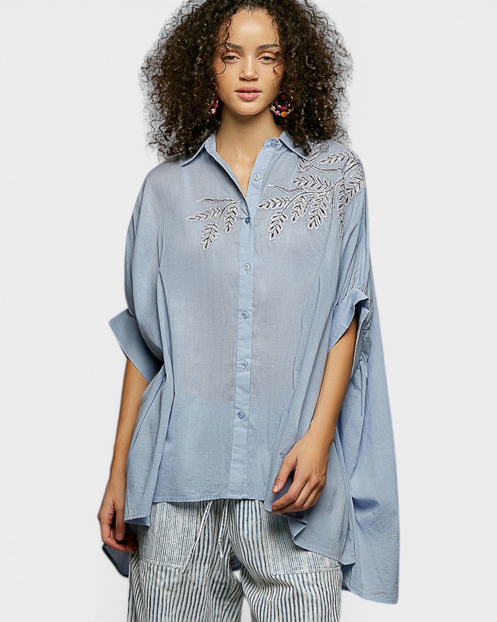 Woman wearing a blue embroidered shirt on a white background