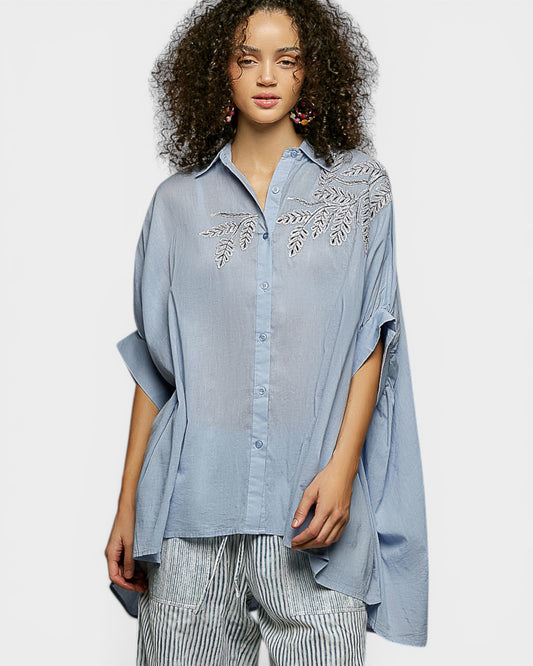 Woman wearing a blue embroidered shirt on a white background