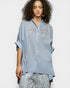 Woman wearing a light blue embroidered shirt on a white background