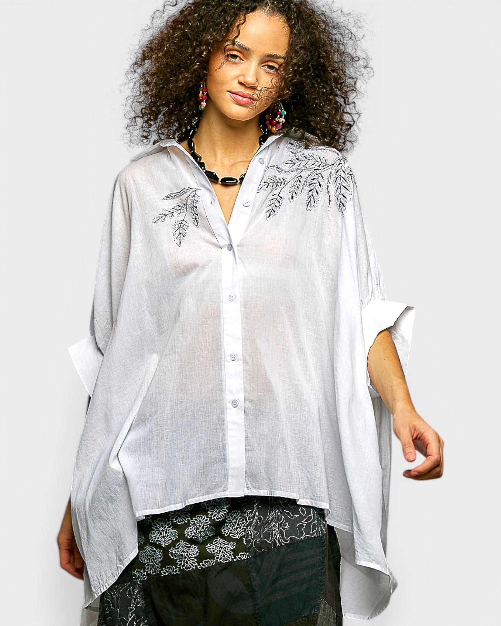 Woman wearing a white embroidered blouse with a plain background