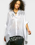 Woman wearing a white embroidered blouse with a plain background