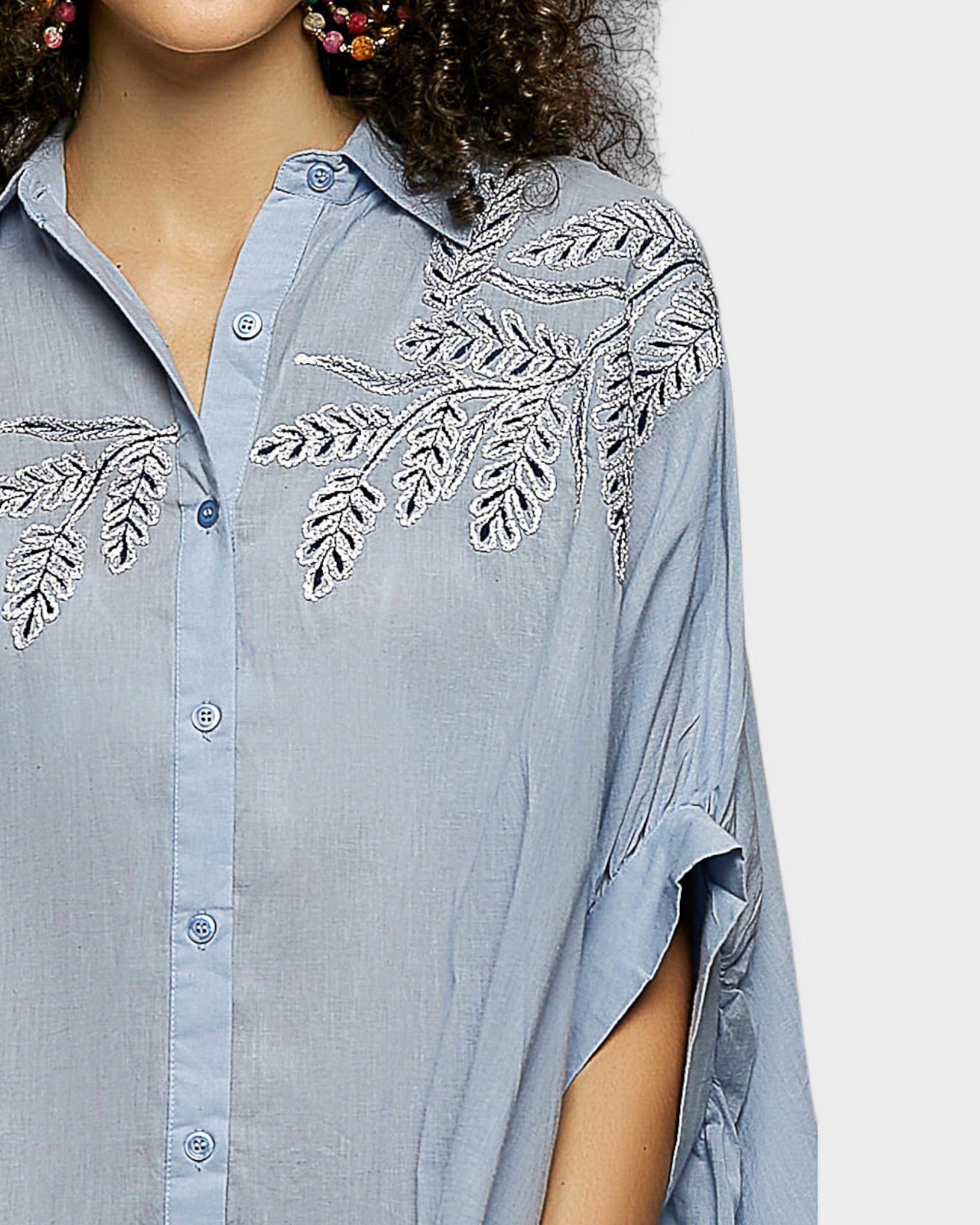 Light blue shirt with floral embroidery on a plain background