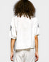 Person wearing a white outfit with black patterns on sleeves against a light gray background