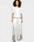 Woman wearing a white outfit with floral embroidery on a plain background