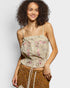Woman wearing a floral embroidered top and brown pants on a plain background