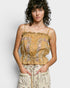 Woman wearing a mustard yellow floral top against a plain background