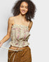 Woman wearing a floral top and brown pants on a plain background