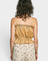 Woman wearing a mustard yellow top with floral patterns on a plain background
