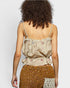 Woman wearing a beige floral top and brown skirt against a plain background
