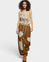 Woman wearing a floral top and brown patchwork pants on a white background