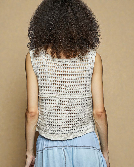 Person wearing a sleeveless crochet top against a beige background