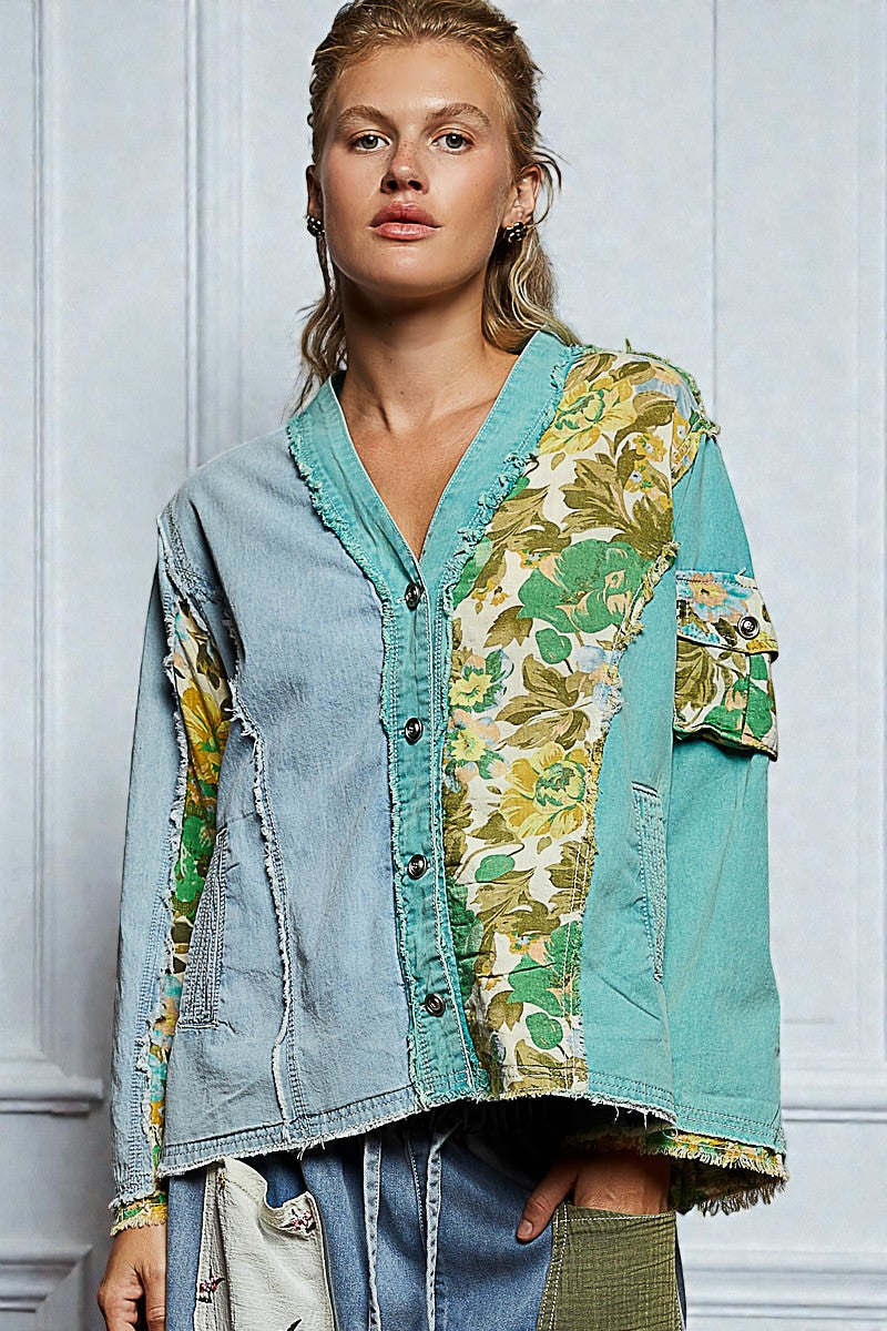 Woman wearing a denim jacket with floral patterns against a light gray wall.