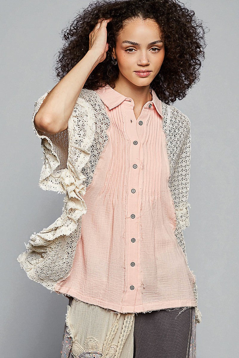 Woman wearing a light pink button-up shirt with a textured cardigan against a gray background