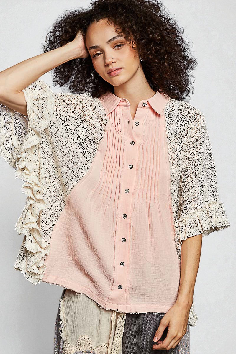 Woman wearing a light pink button-up shirt with a floral kimono over it on a white background