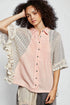 Woman wearing a light pink button-up shirt with a floral kimono over it on a white background