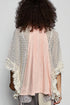 Person wearing a light pink pleated top with a textured beige cardigan against a plain background