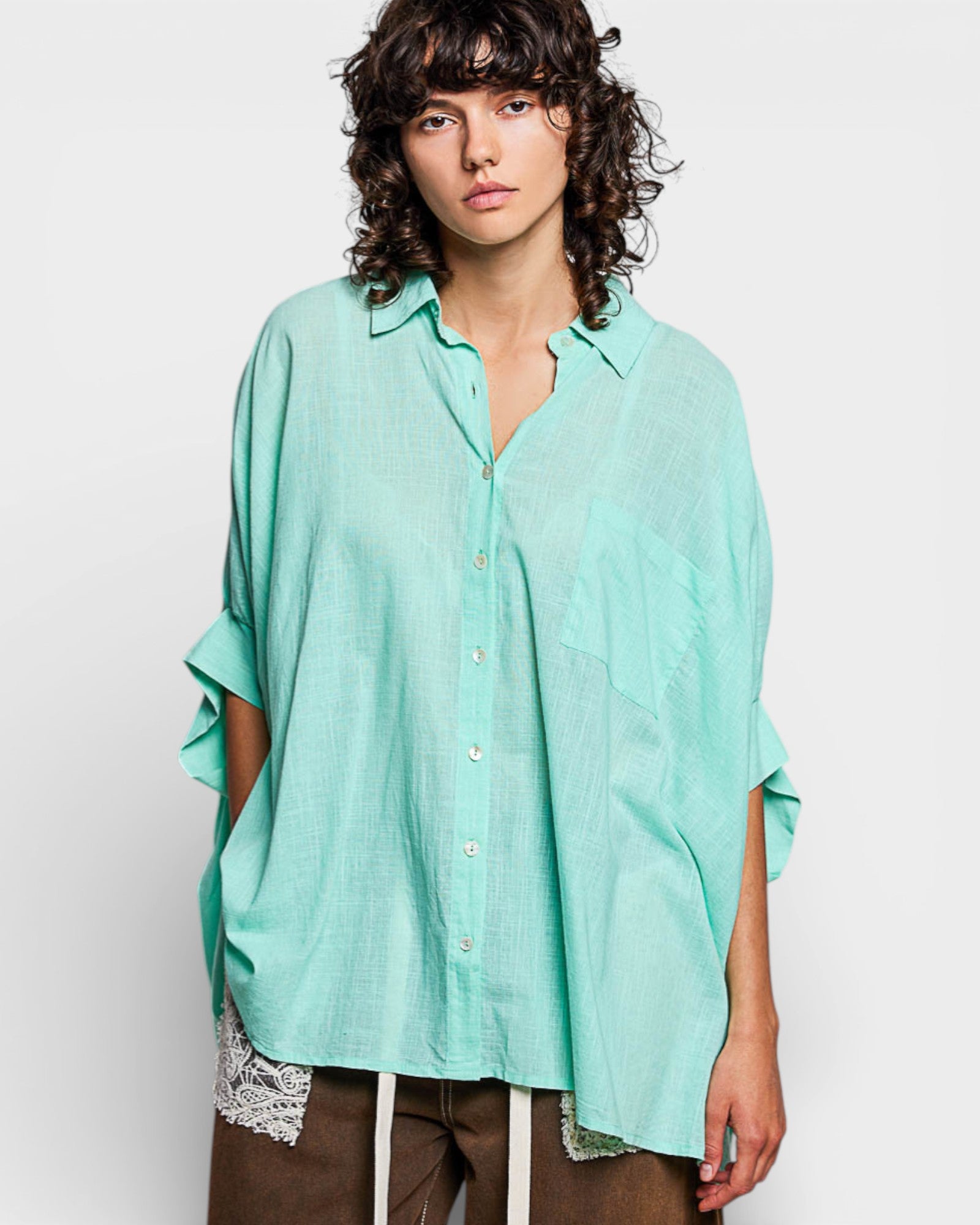 Person wearing a light green oversized shirt on a white background