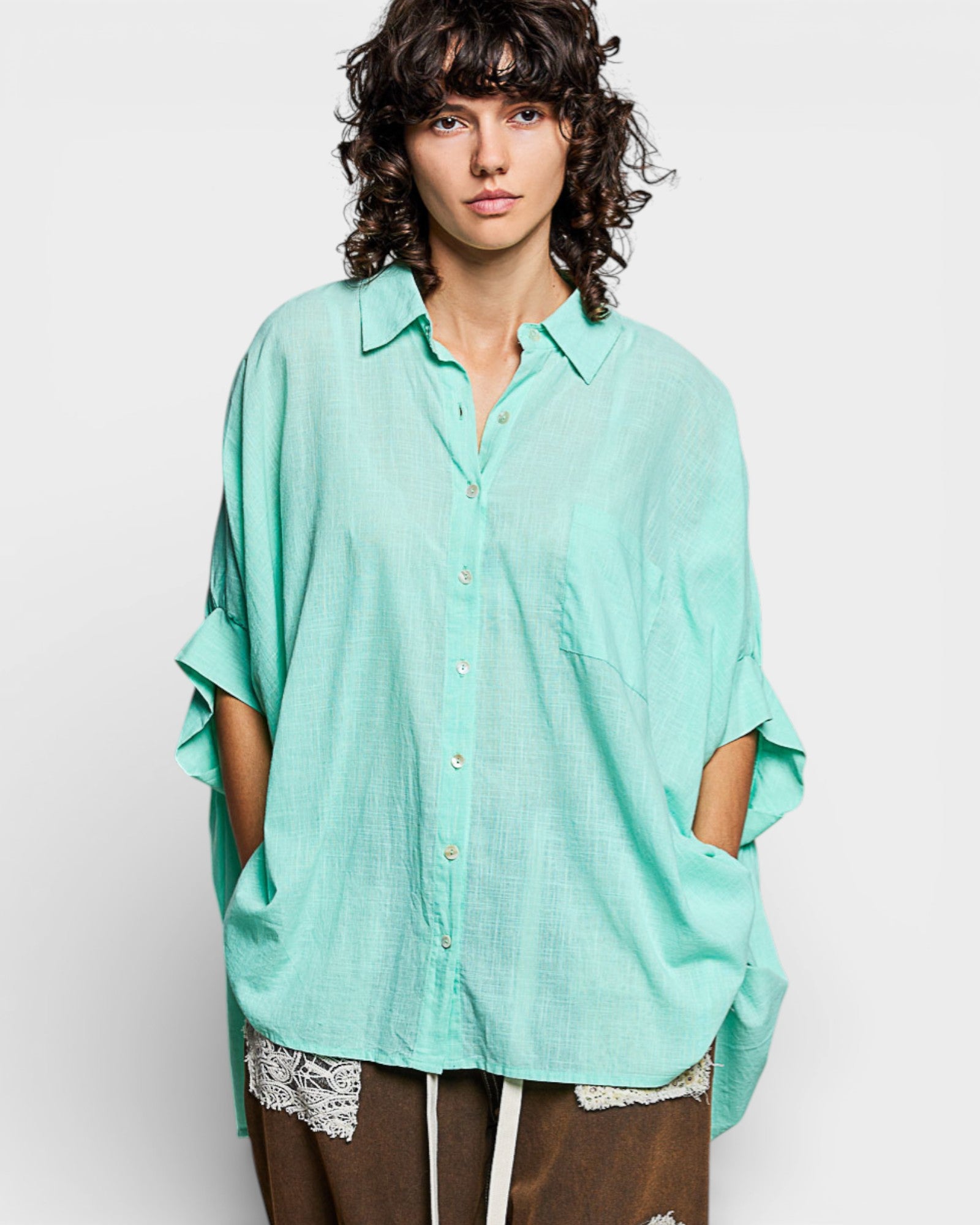 Person wearing a light green oversized shirt against a white background