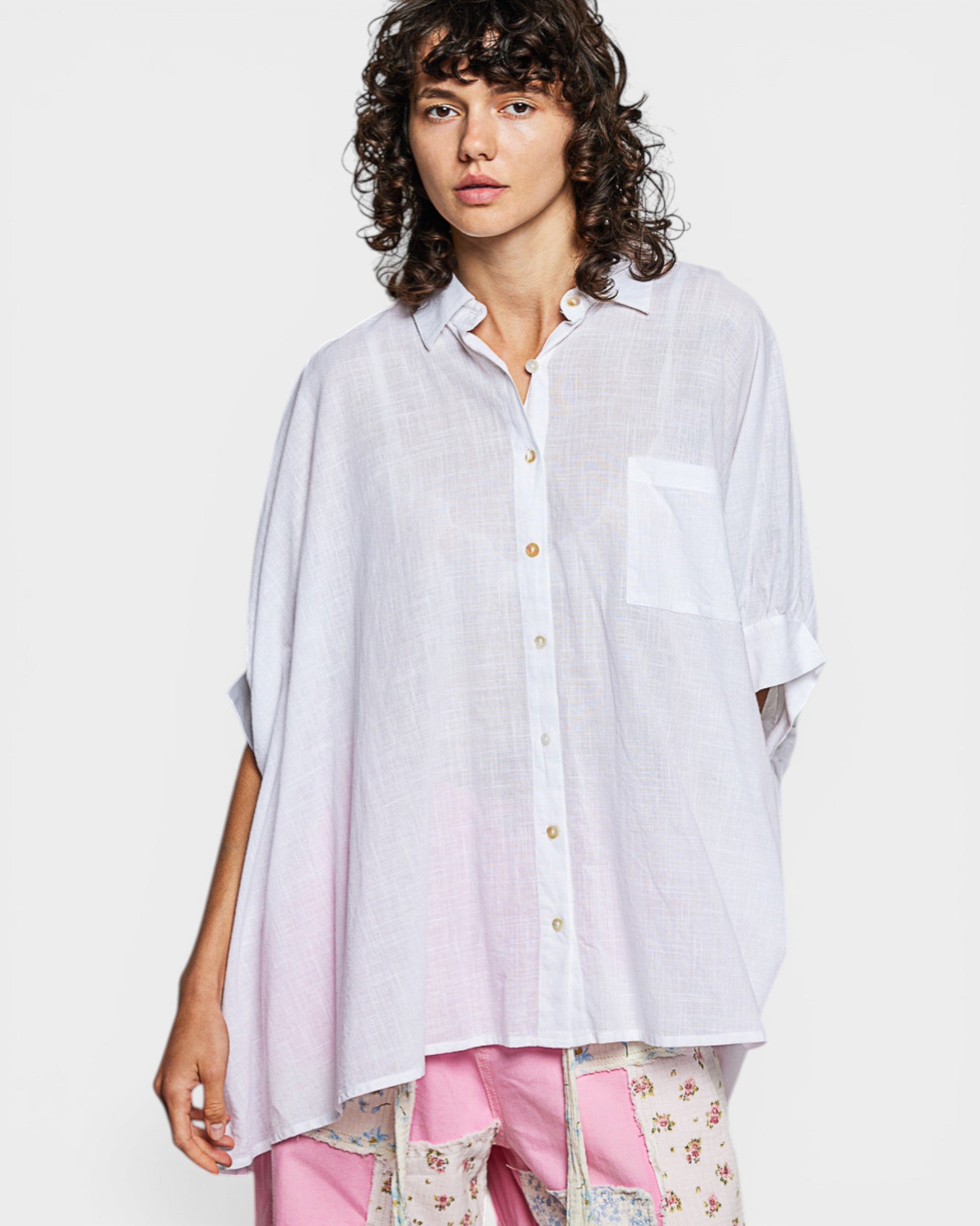 Person wearing a light-colored button-up shirt with a white background