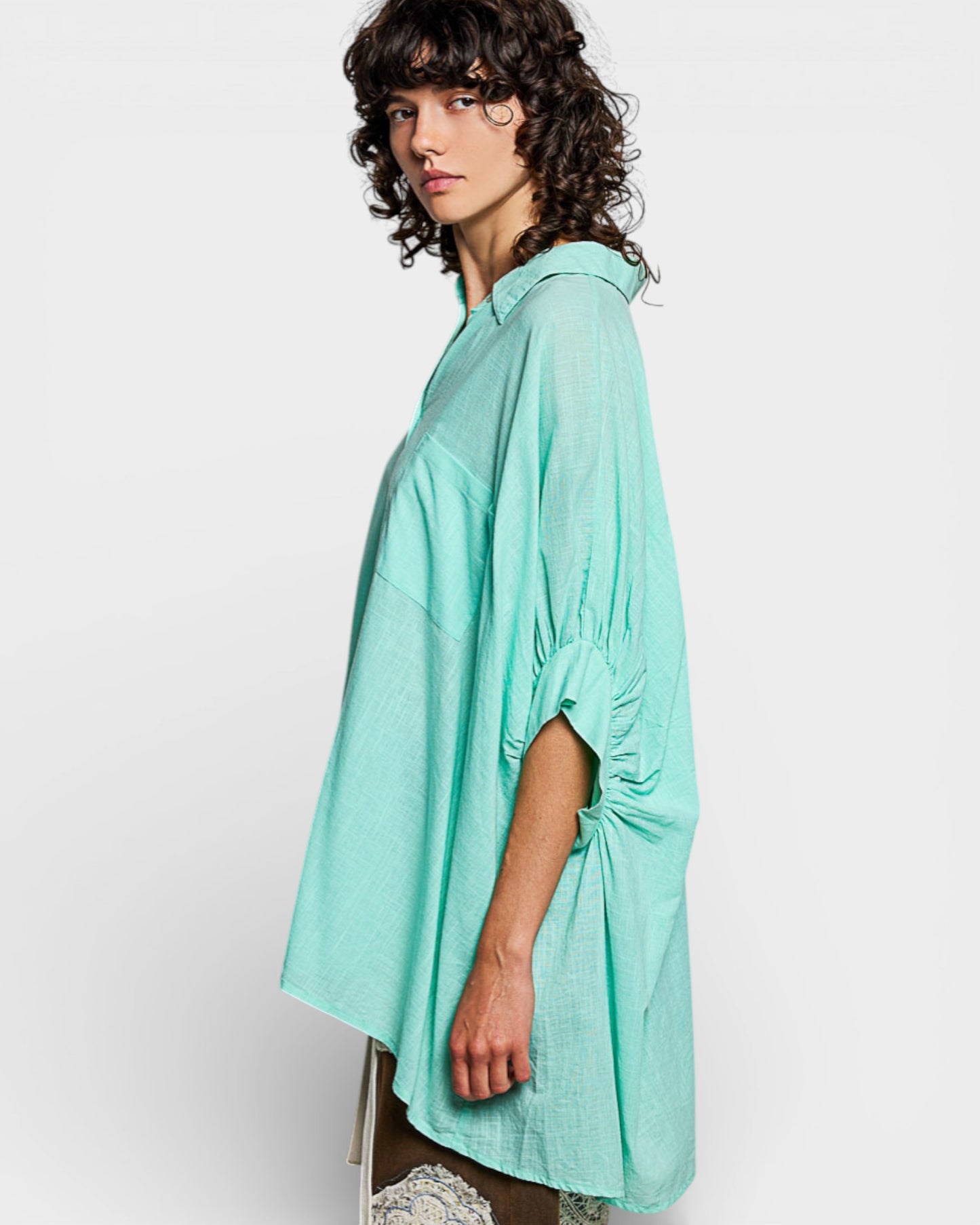 Woman wearing a light green oversized shirt on a white background