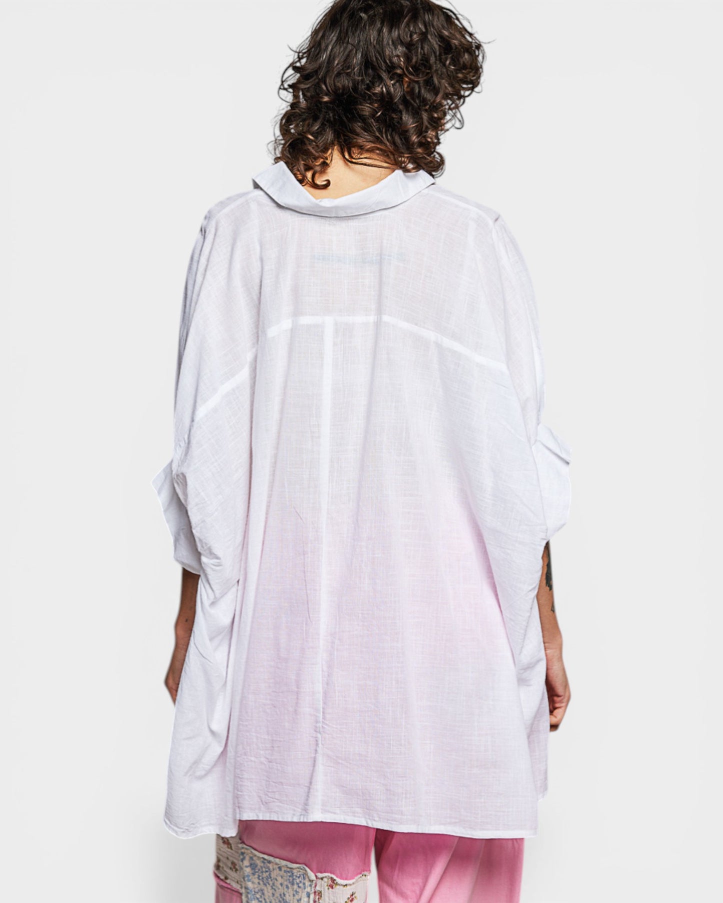 Person wearing a white shirt with a light pink gradient on a white background