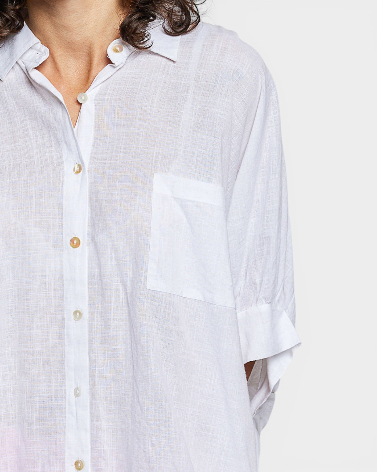 Close-up of a person wearing a light-colored shirt with short sleeves on a white background