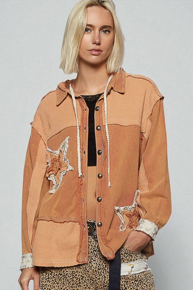 Woman wearing a brown patchwork jacket with star designs on a plain background