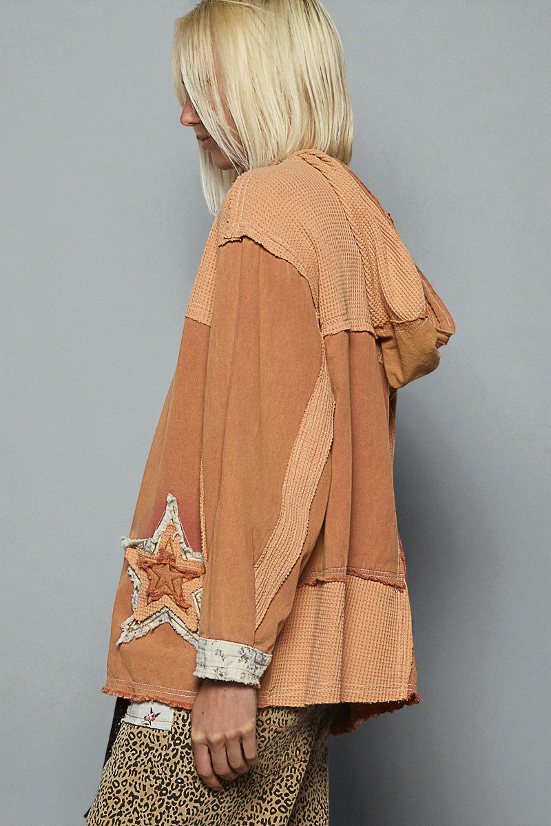 Person wearing a brown jacket with star design on a gray background