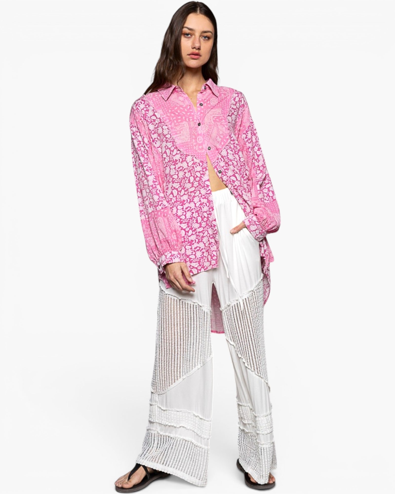 A model wearing a pink floral long-sleeve button-up shirt and white wide-leg sheer crochet pants against a plain white background.