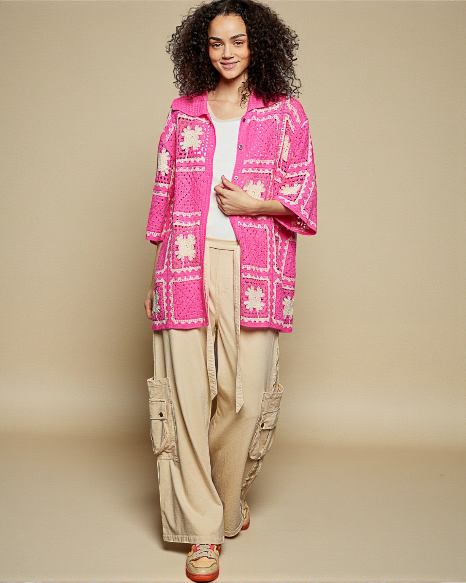 Woman wearing a bright pink patterned jacket on a beige background