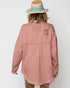 Person wearing a pink denim jacket with back patches on a white background