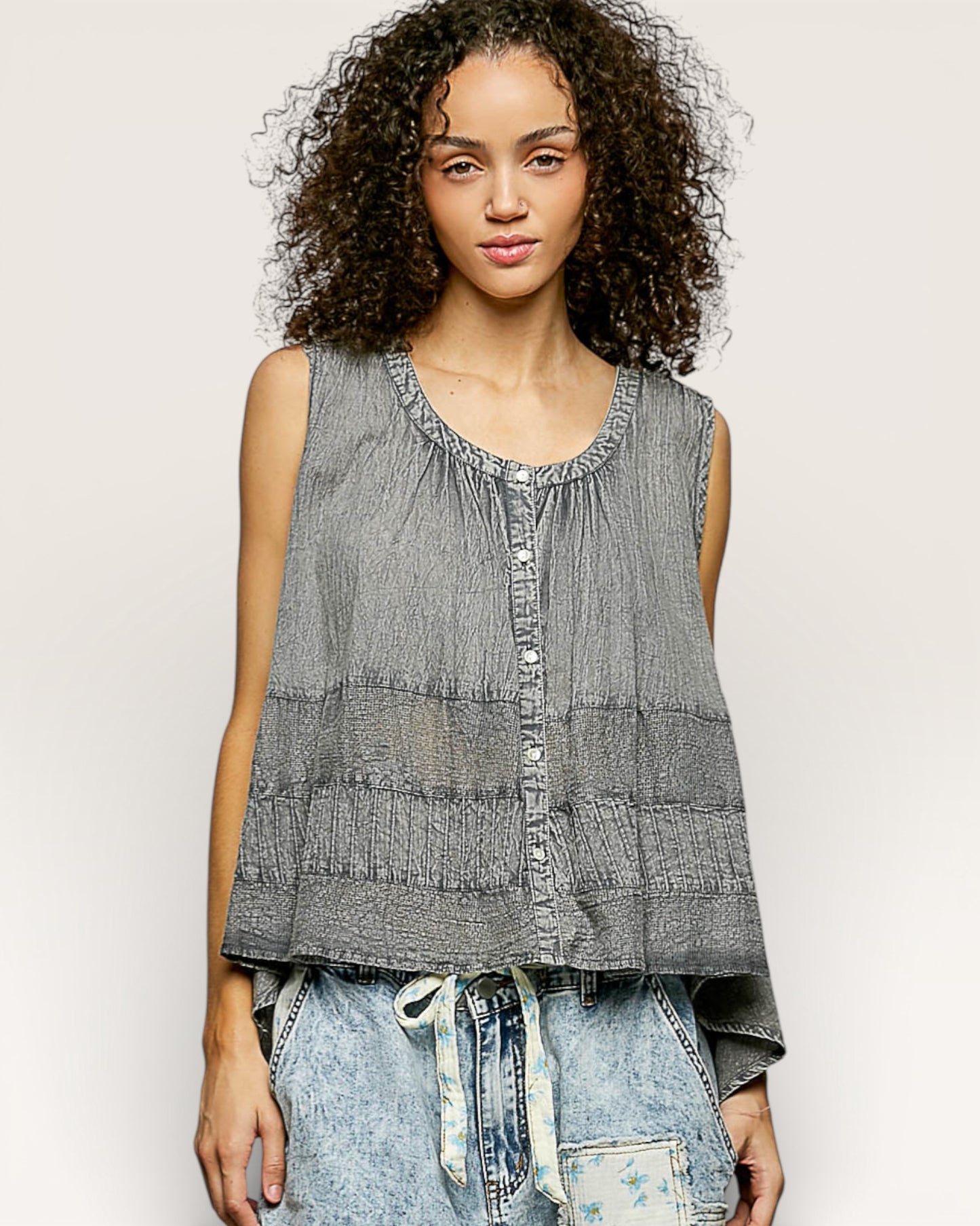 Woman wearing a sleeveless denim top with a plain background