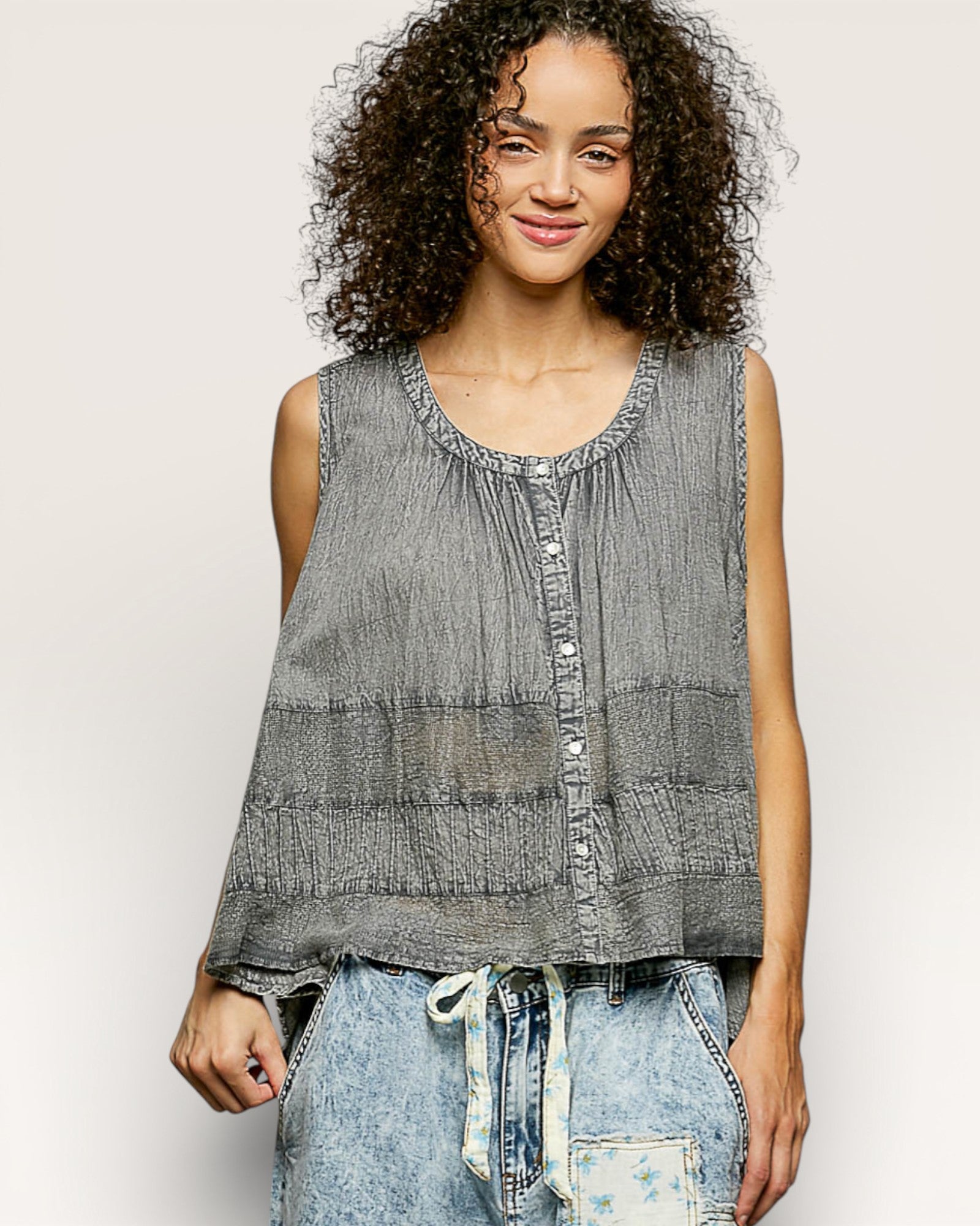 Woman wearing a sleeveless gray top with a white background