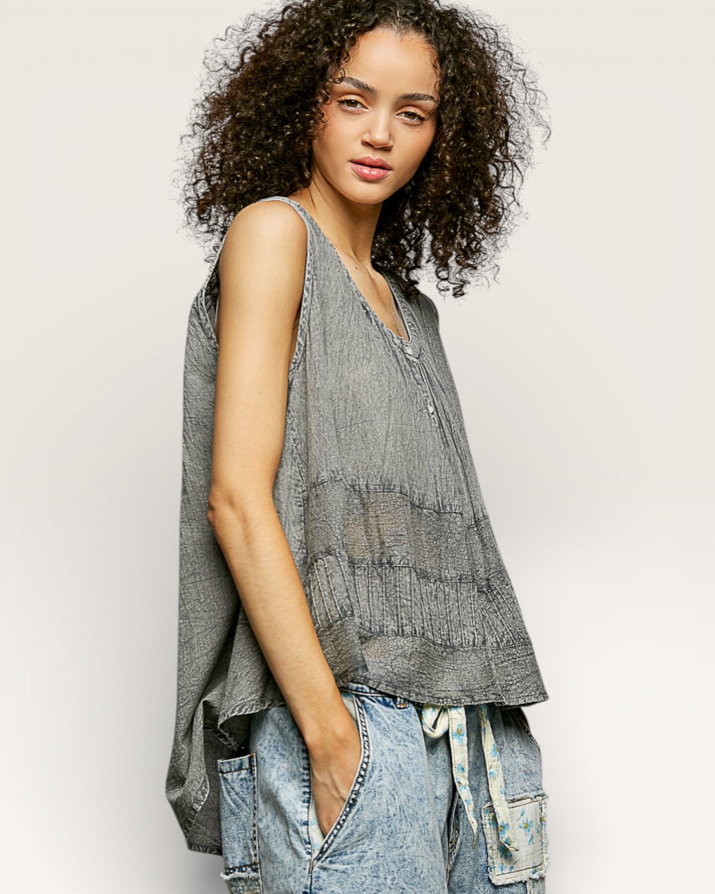 Woman wearing a sleeveless, layered top with a neutral background